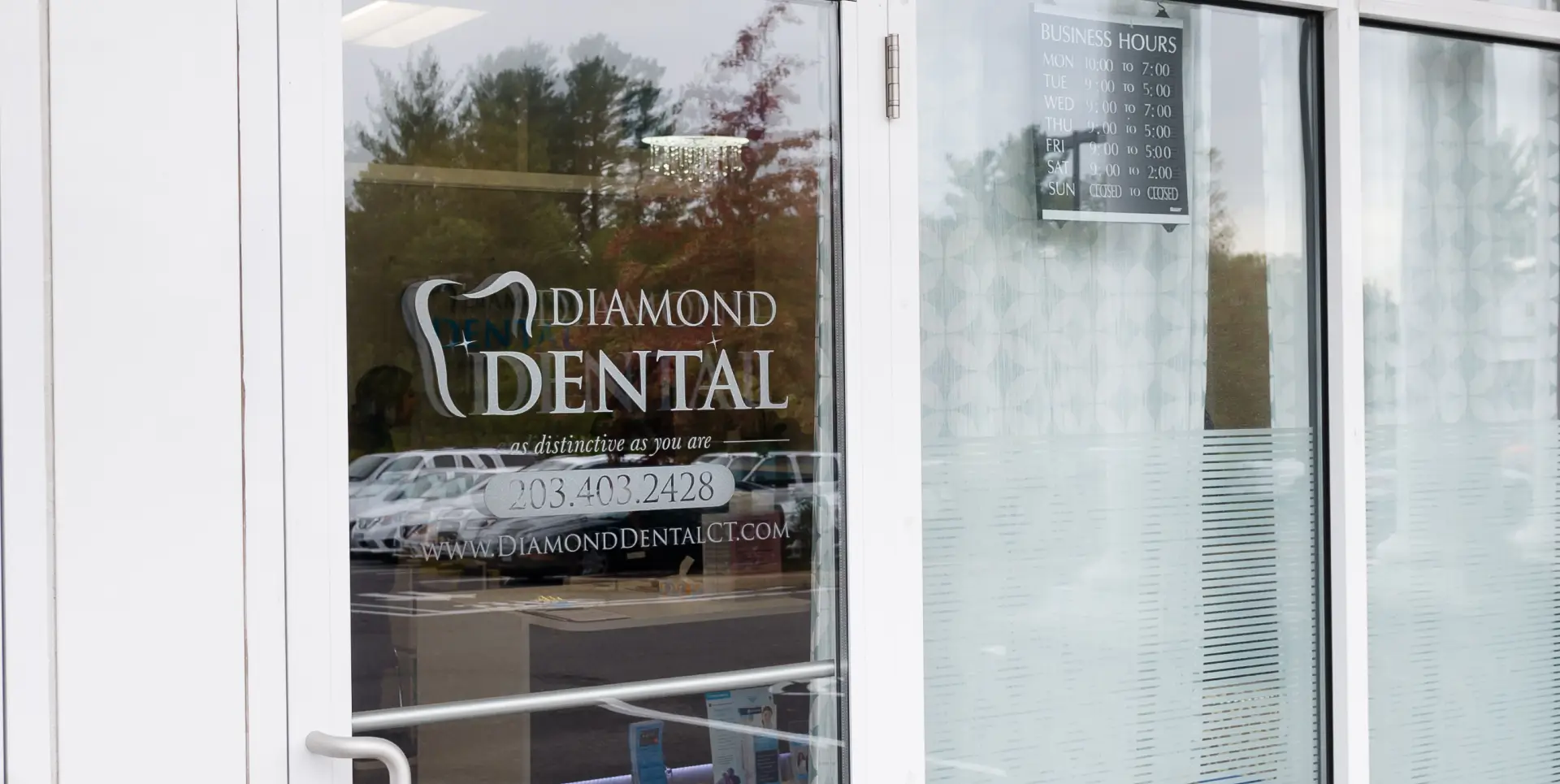 Glass door of a dental clinic displaying the name "Diamond Dental" and contact information.